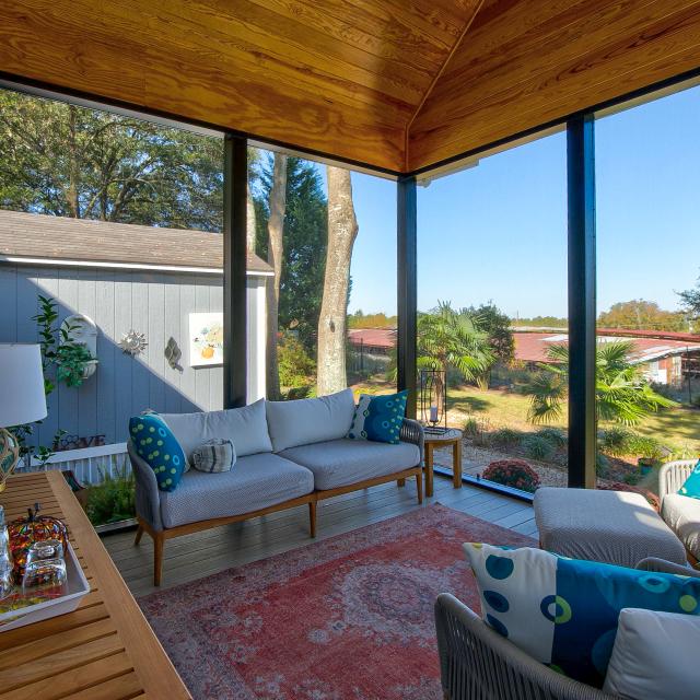 View of the inside of a screened back porch facing the couch.