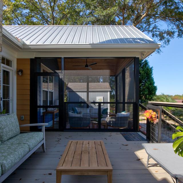 View of screened section of a screened back porch from the unscreened section of the back porch. 