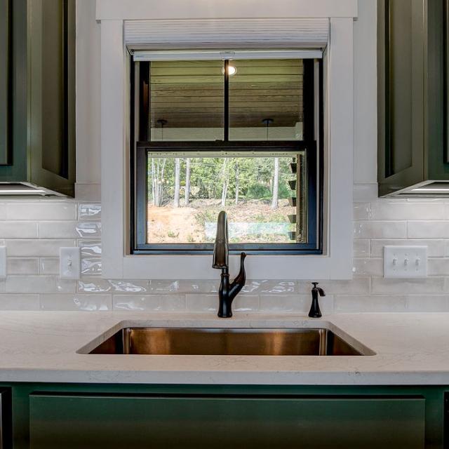 Custom Rafter B kitchen featuring stone countertops and stainless steel appliances in a lakeside home