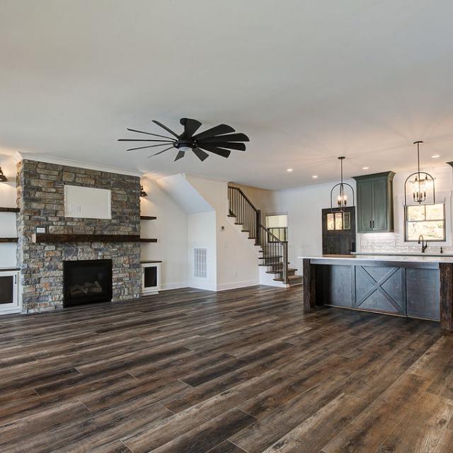 Custom Rafter B living room featuring stone fireplace and large open sliding glass doors in a lakeside home