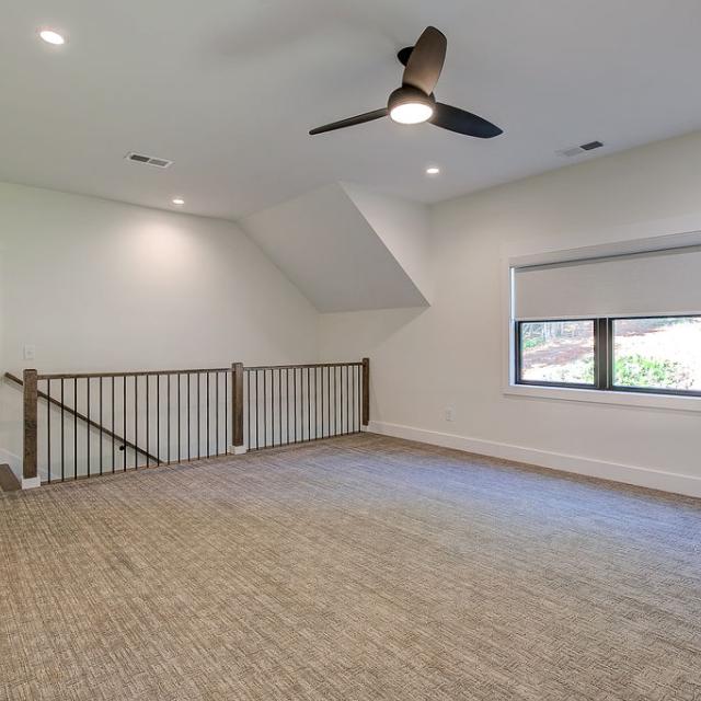 Carpeted interior room with railing