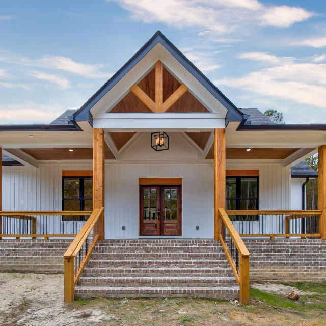 Front porch of white craftsman style home with wood accents