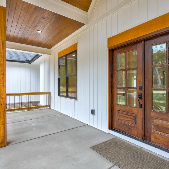 Front porch of white craftsman style home with wood accents