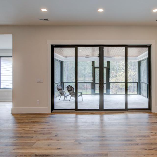 Room with white walls and wooden floors with glass doors to back porch - Rafter B Construction custom home