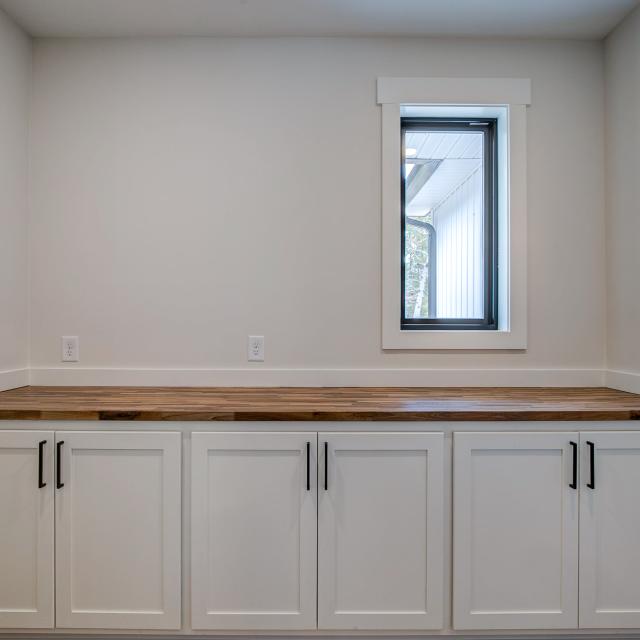 Butler's Pantry off of the main kitchen with white cabinets and prep space