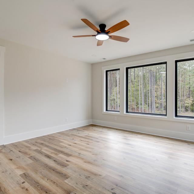 Room with wood floors, white walls and large windows and ceiling fan