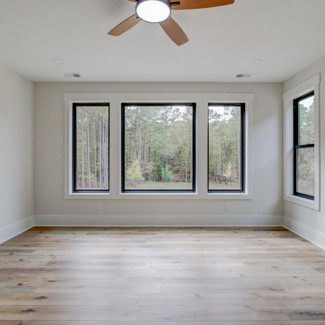 Room with wood floors, white walls and large windows and ceiling fan