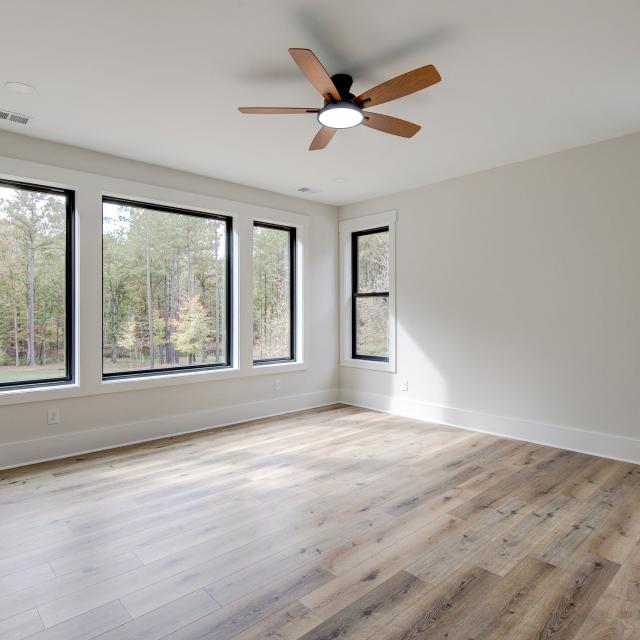 Room with wood floors, white walls and large windows and ceiling fan