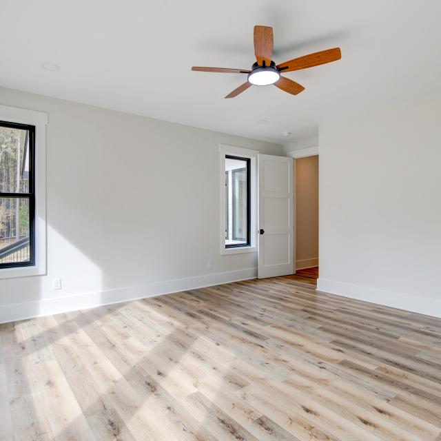 Room with wood floors, white walls and large windows and ceiling fan