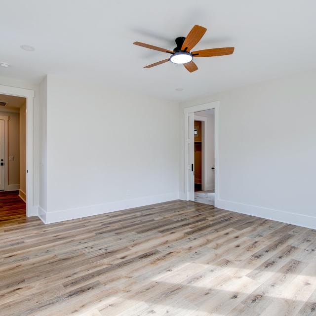 Room with wood floors, white walls and large windows and ceiling fan