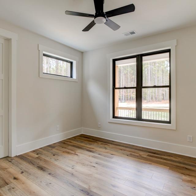 Room with wood floors, white walls and large windows and ceiling fan