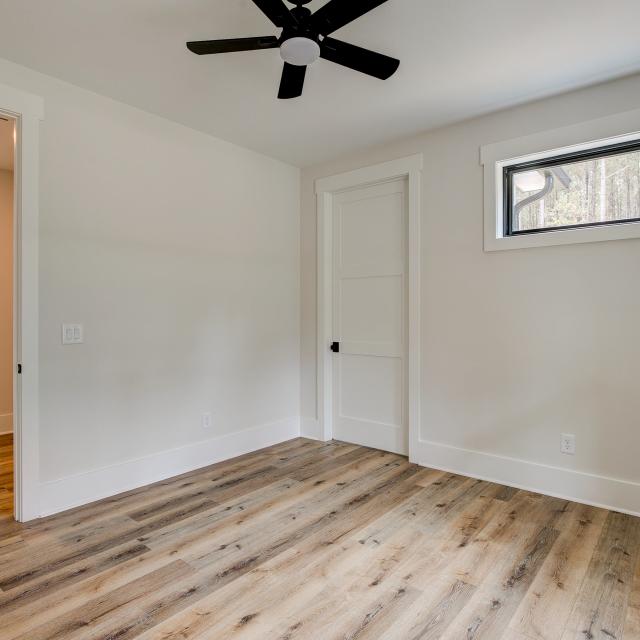 Room with wood floors, white walls and large windows and ceiling fan