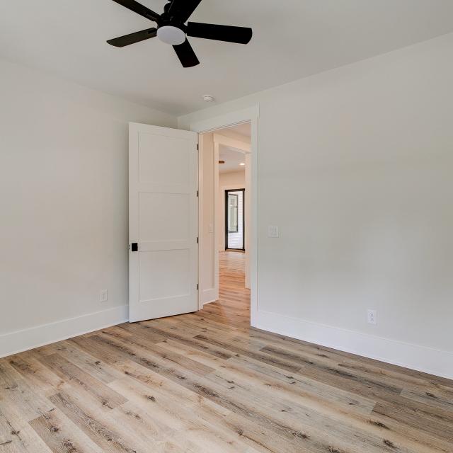 Room with wood floors, white walls and large windows and ceiling fan